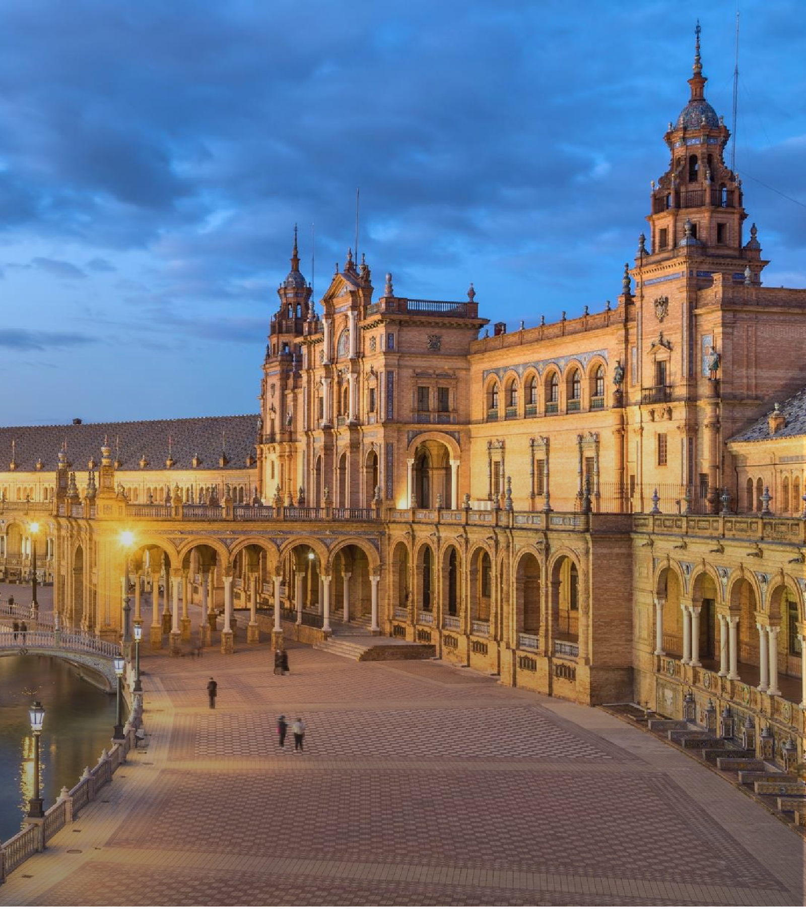 Plaza de Espana in Seville illuminated at dusk with its grand curved building and tower