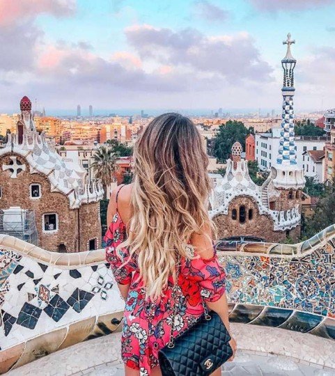 Woman in a floral dress overlooking Park Guell mosaic architecture in Barcelona